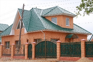 Красный кирпичный дом с зеленой крышей
